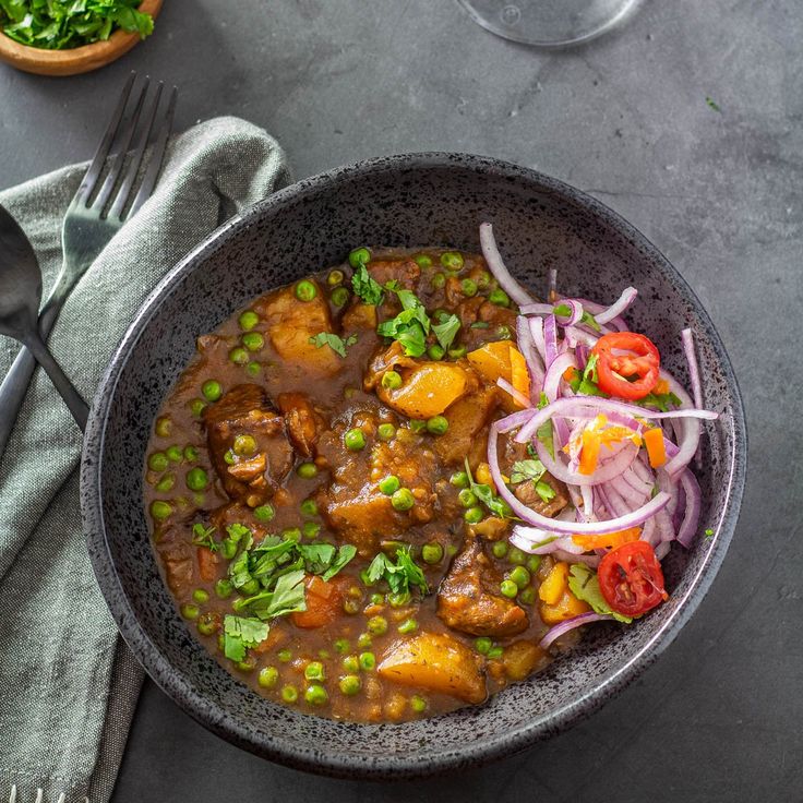 a bowl filled with meat and vegetables on top of a table next to a fork