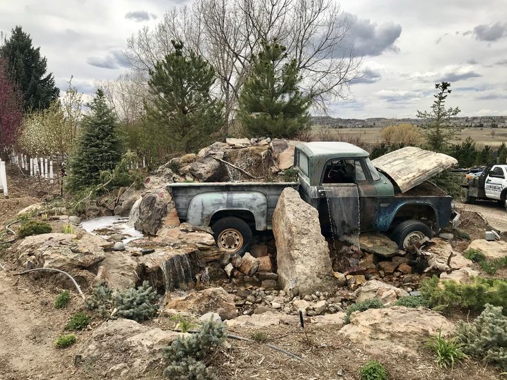 an old pick up truck sitting on top of a pile of rocks