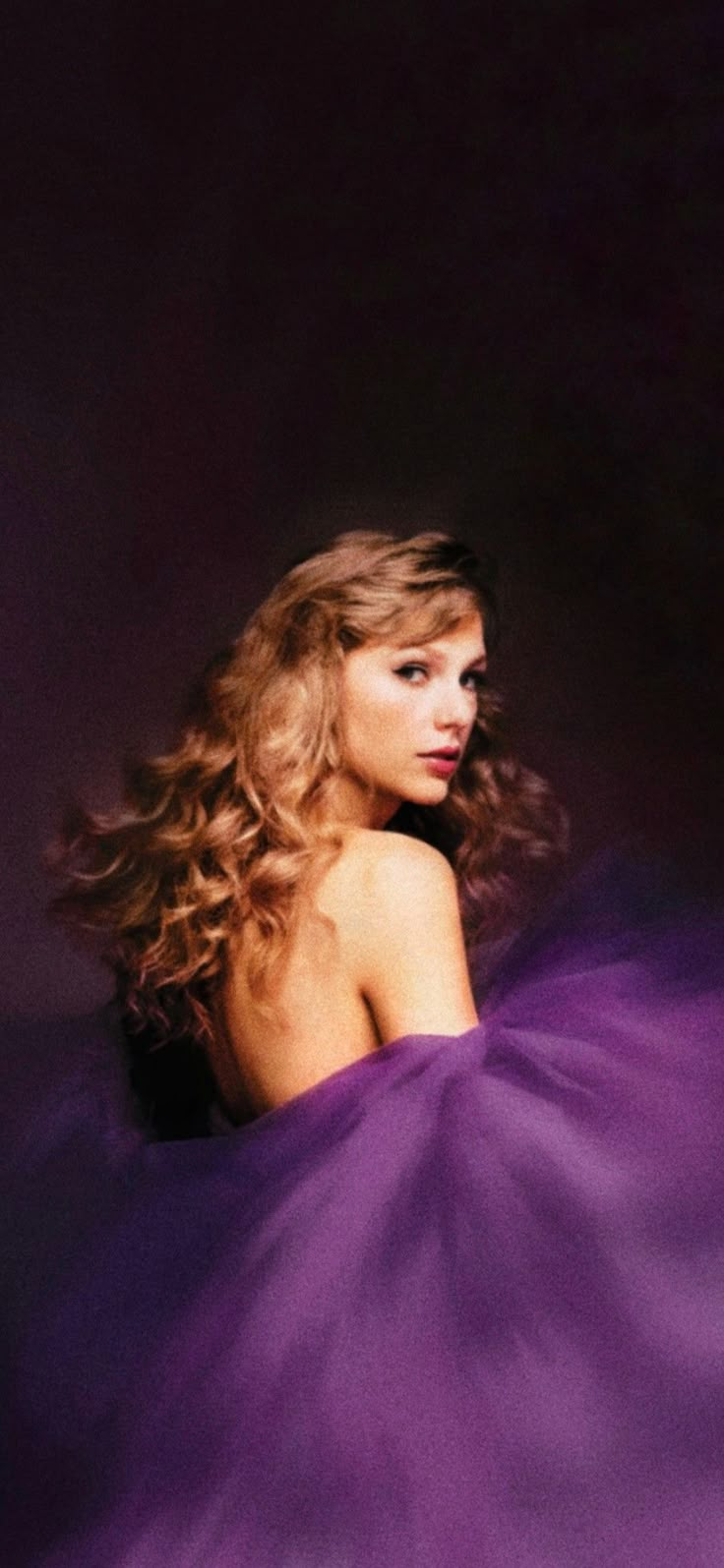 a woman in a purple dress is posing for the camera with her hair blowing up