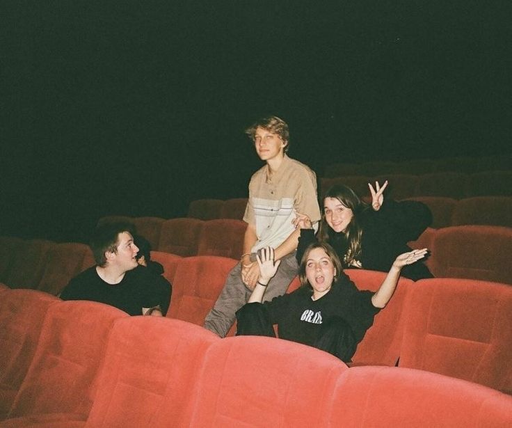 some people are sitting in an empty theater seat and one person is waving at the camera