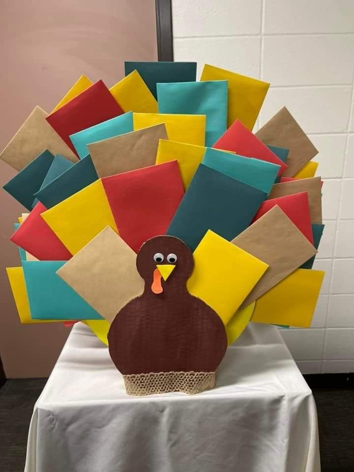 a turkey made out of paper sitting on top of a white tablecloth covered table