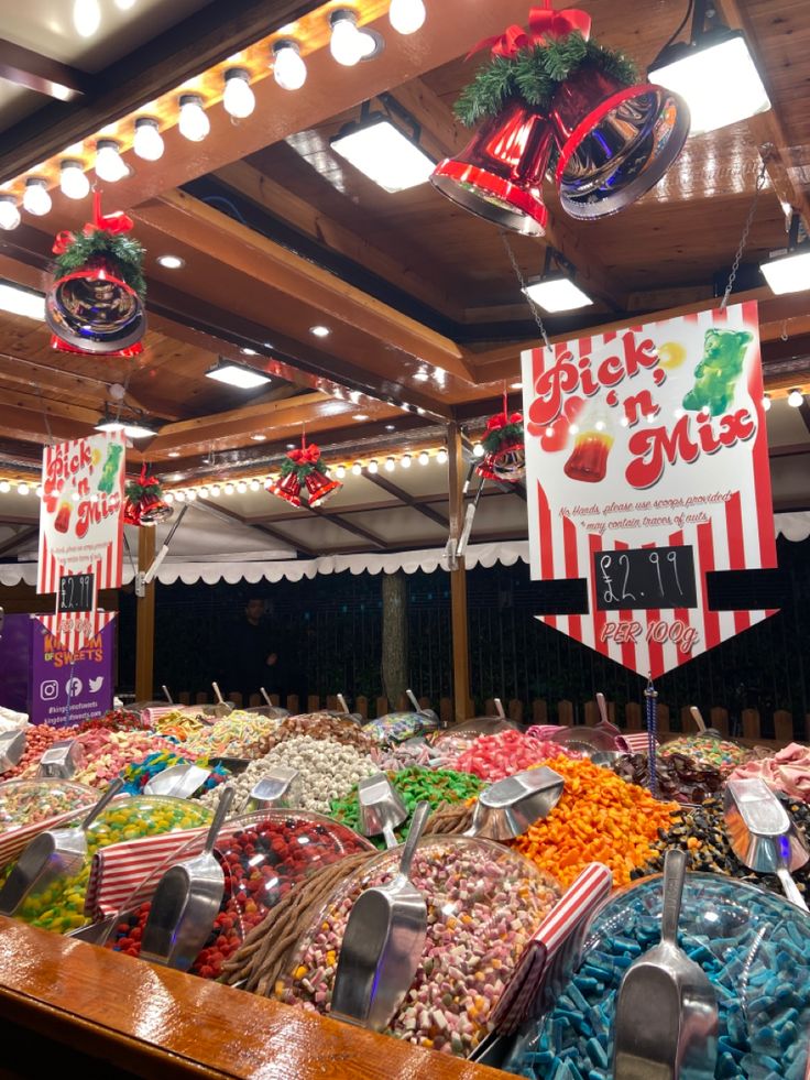 an assortment of candy and candies for sale in a market place with lights on the ceiling