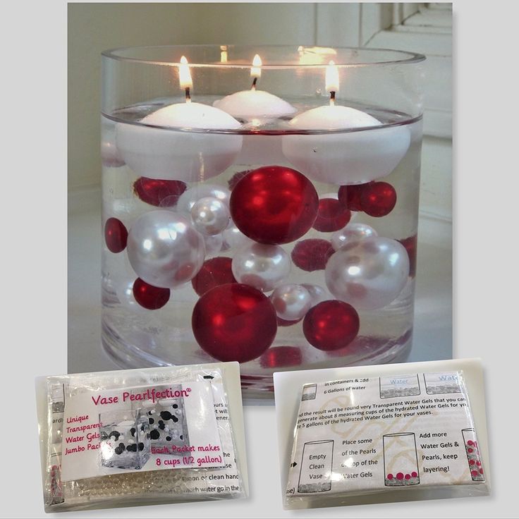 a glass vase filled with red and white balls next to a packet of wax paper