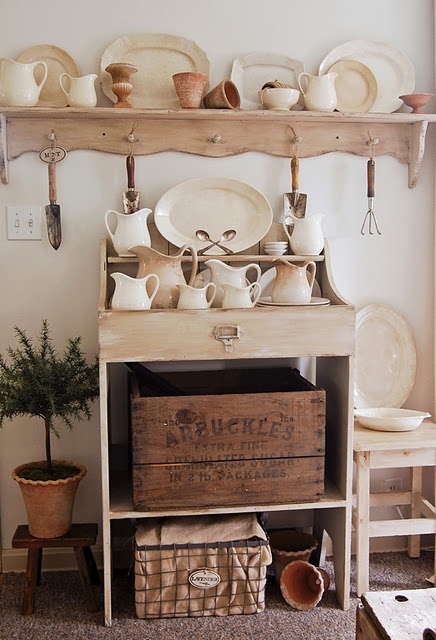 a shelf filled with lots of plates and bowls on top of wooden crates next to a potted plant