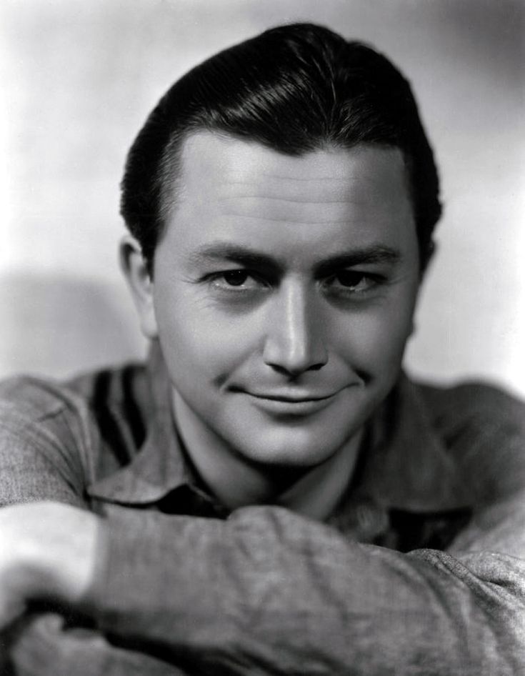 a black and white photo of a man with his hands on his chest, smiling at the camera