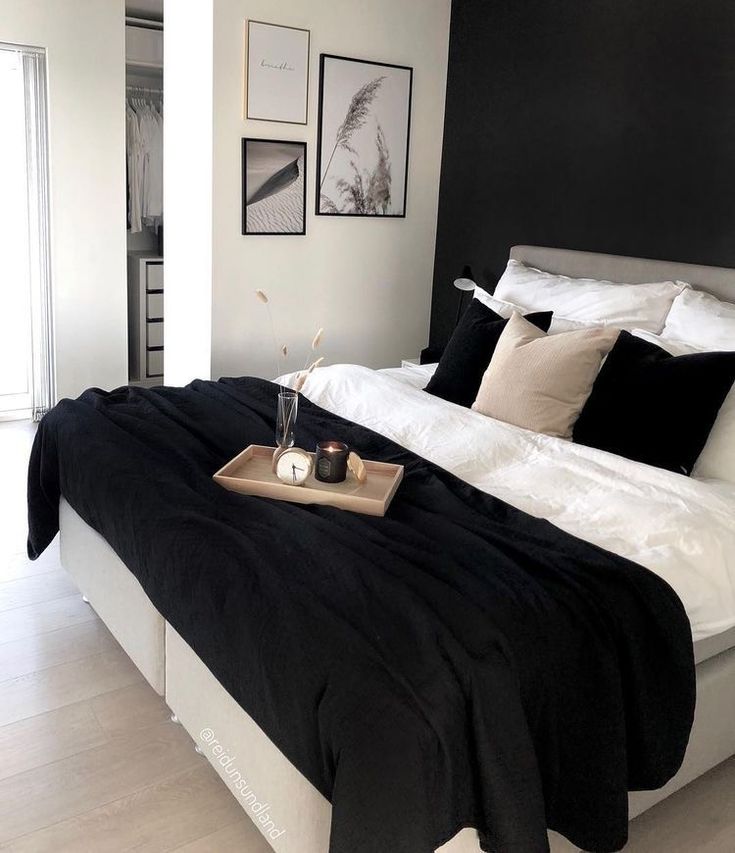 a black and white bedroom with pictures on the wall above the bed, along with a tray full of candles