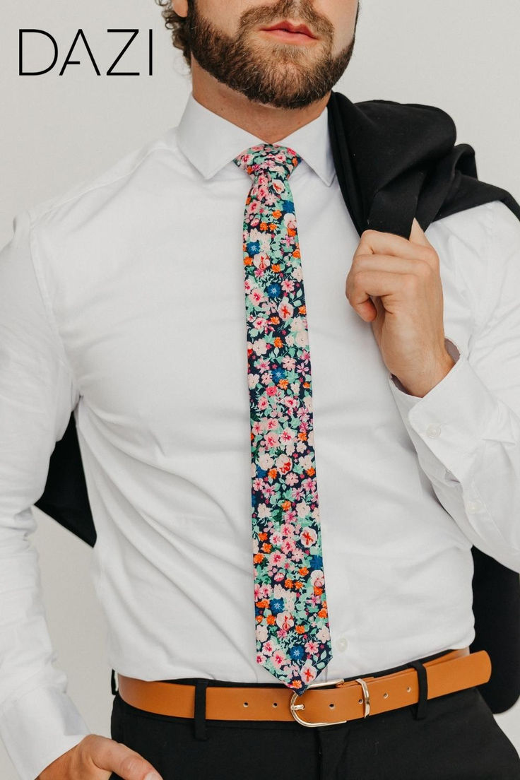 a man wearing a white shirt and flowered tie is posing for the camera with his hands in his pockets