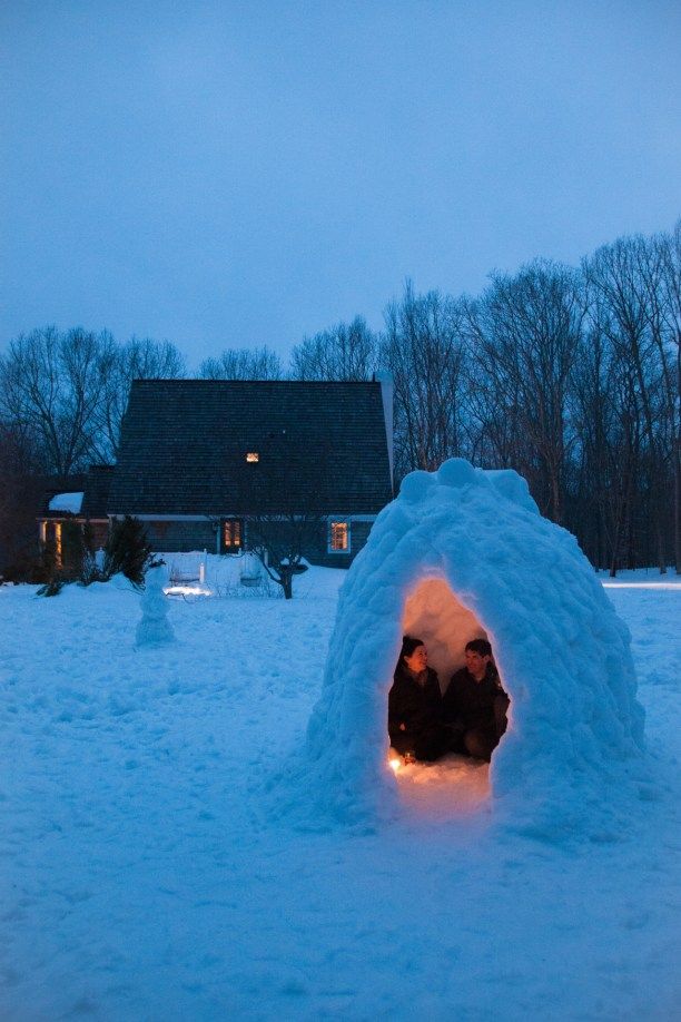 two people are sitting in an igloose that is made out of snow