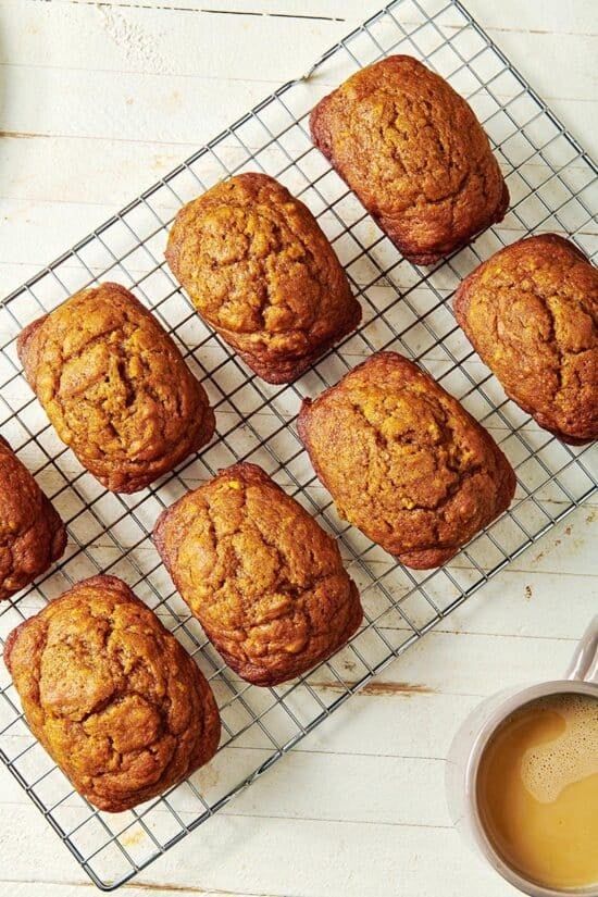 muffins cooling on a wire rack next to a cup of coffee