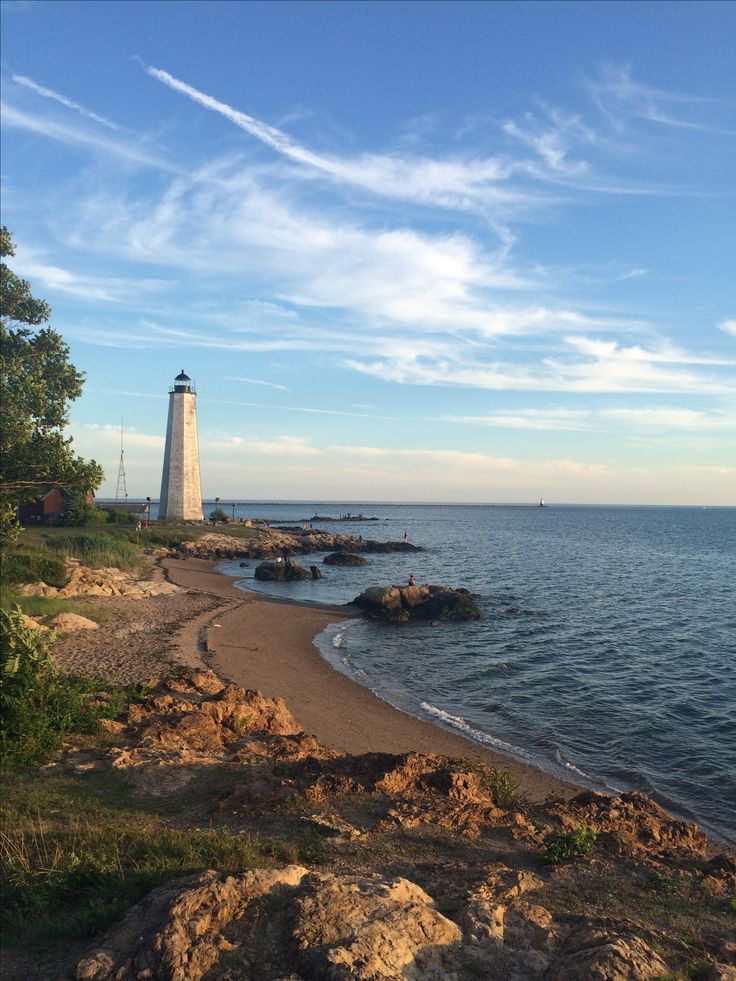 a light house sitting on top of a rocky shore next to the ocean and trees