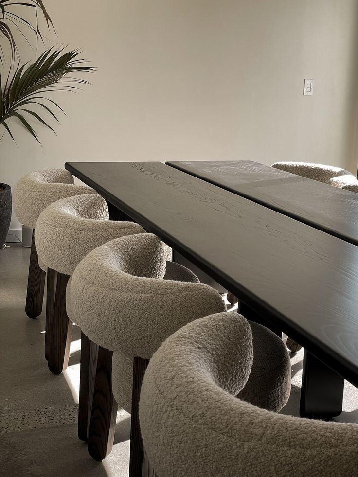 a long table with six chairs and a potted plant in the corner next to it