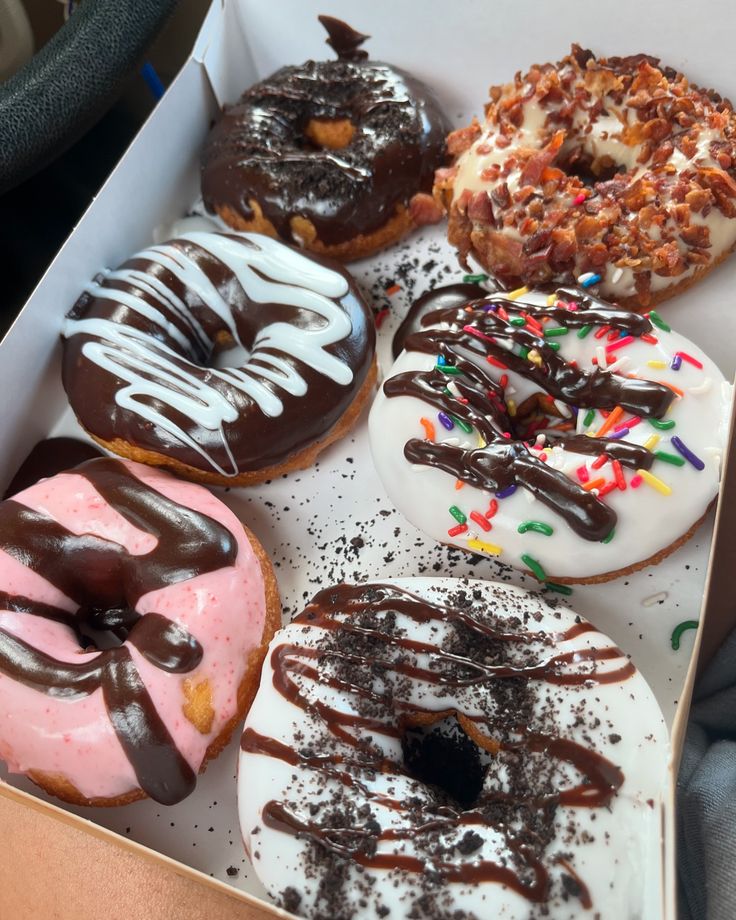 a box filled with different flavored donuts covered in frosting and sprinkles