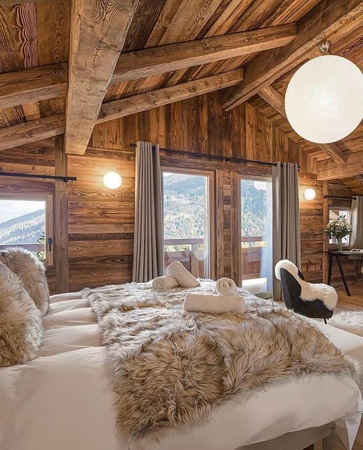 a bedroom with wooden walls and ceilings has white fur on the bed