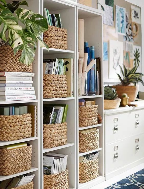 a white bookcase filled with lots of books next to a blue and white rug