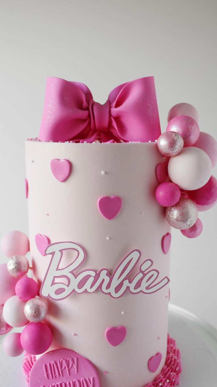 a pink and white cake with hearts on it's side, decorated with balloons