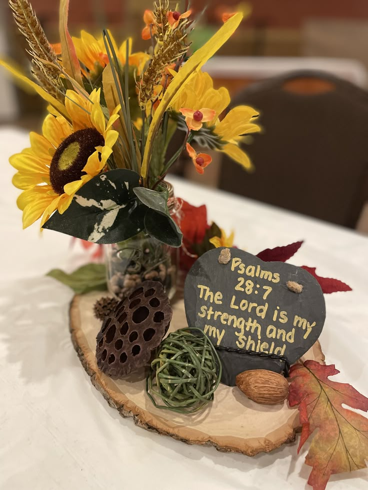 a vase filled with sunflowers and other flowers on top of a wooden slice