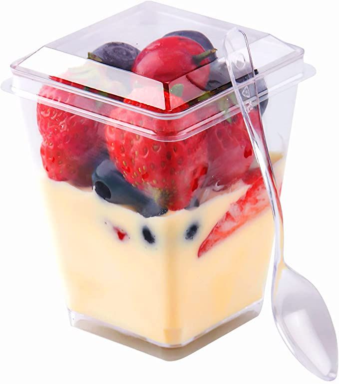 a plastic container filled with fruit and yogurt on top of a white table