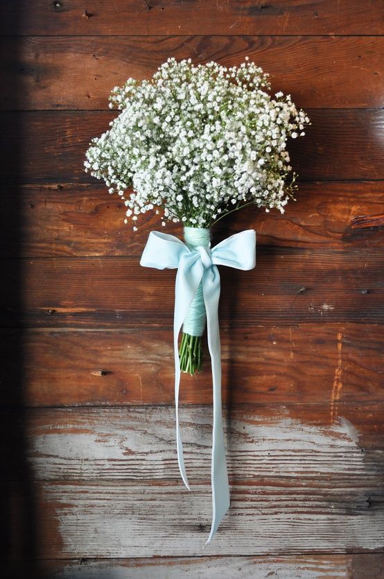 a bouquet of baby's breath tied to a wooden wall with the words love is in the details