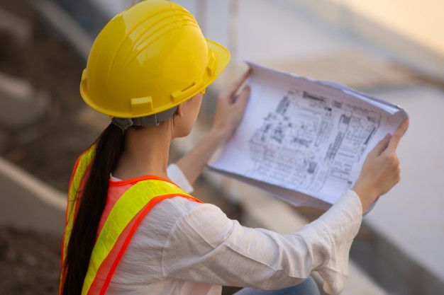 a woman wearing a hard hat and safety vest holding a piece of paper