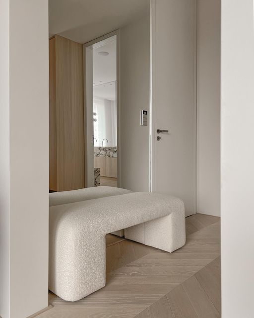 a white bench sitting in the middle of a room next to a door and window