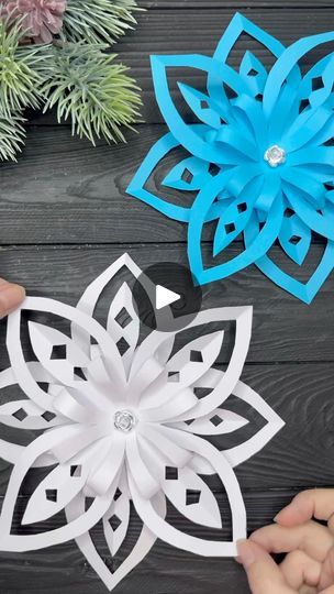 three paper snowflakes sitting on top of a wooden table