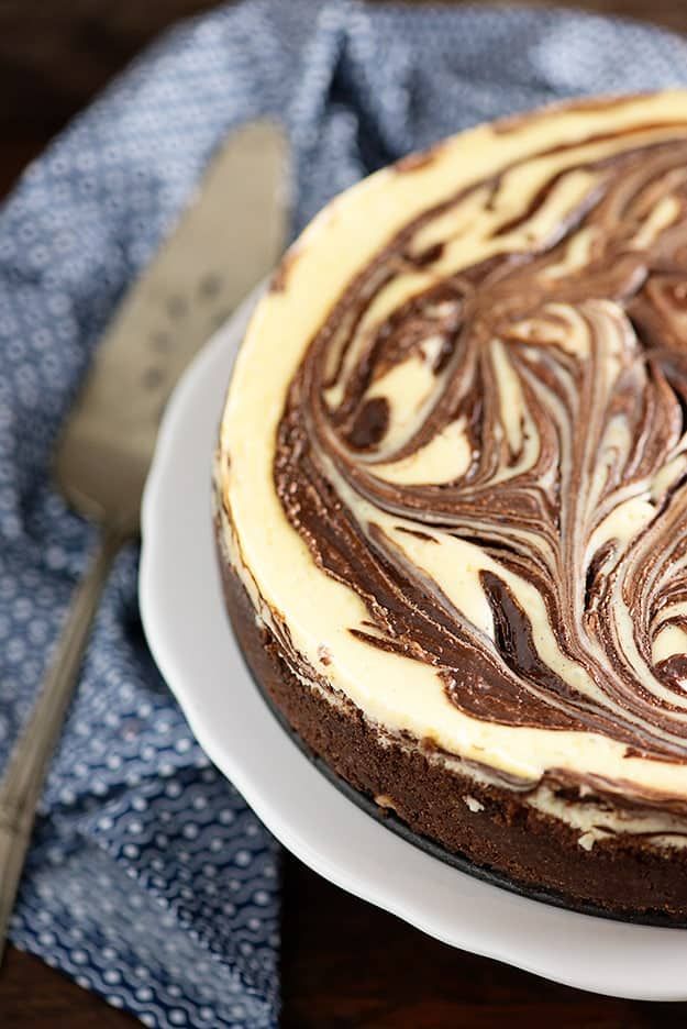 a chocolate cake with white frosting on a plate next to a knife and fork