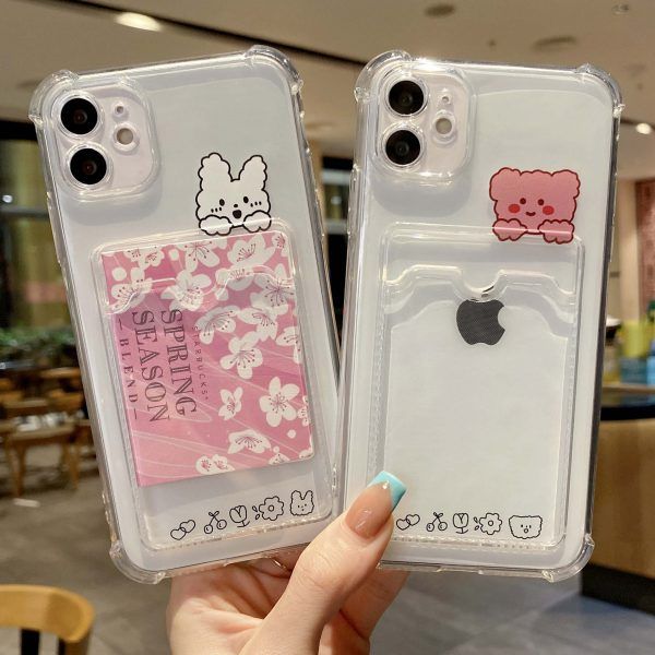 two clear cases with stickers on them are held up by someone's hand