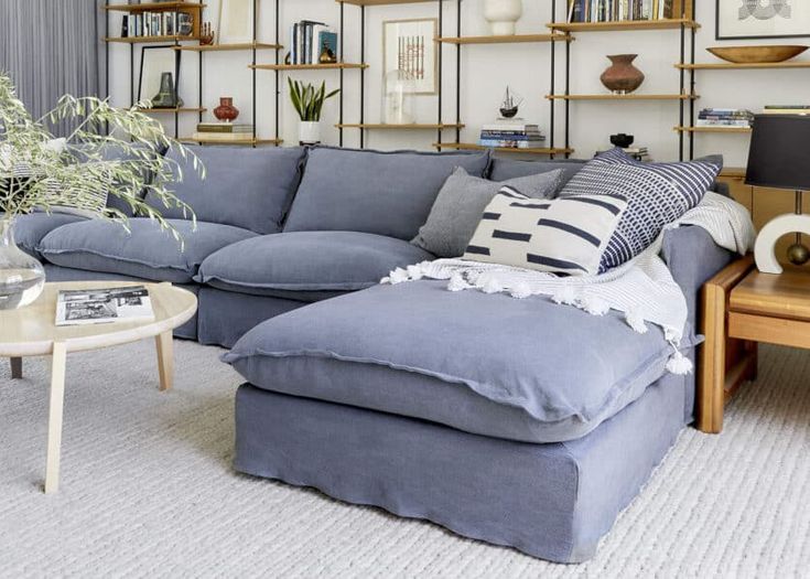 a living room with blue couches and bookshelves on the wall behind them