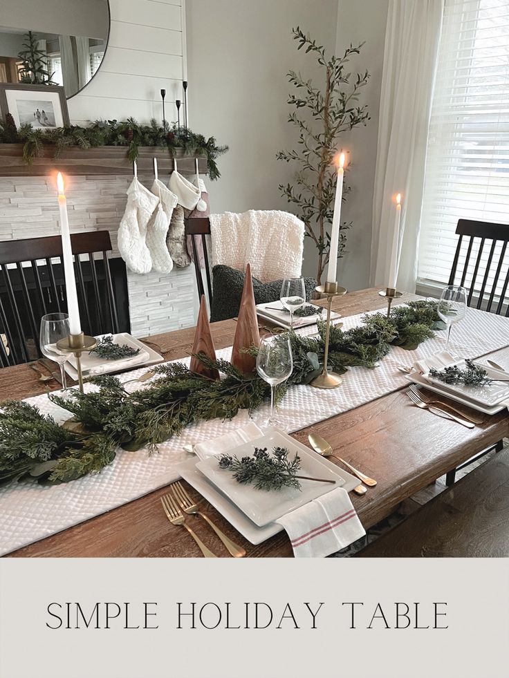 a simple holiday table setting with candles, greenery and napkins on the table