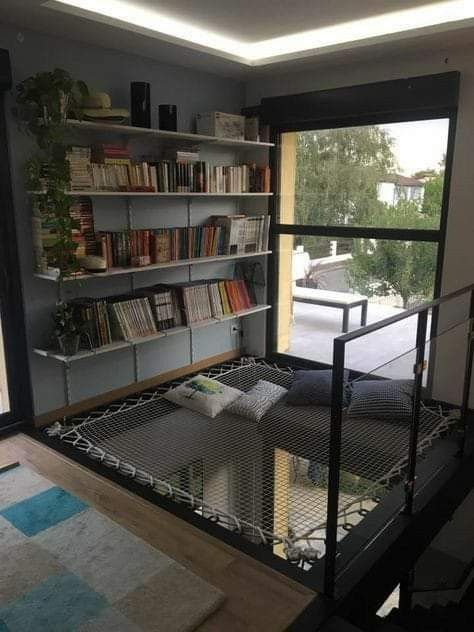 a living room filled with furniture and bookshelves next to a large open window