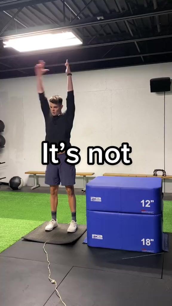 a man standing on top of a black mat holding his arms up in the air