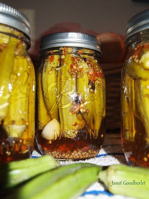 three jars filled with pickled vegetables sitting on top of a table next to corn