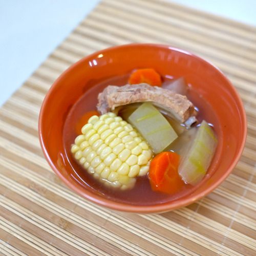 an orange bowl filled with soup and vegetables