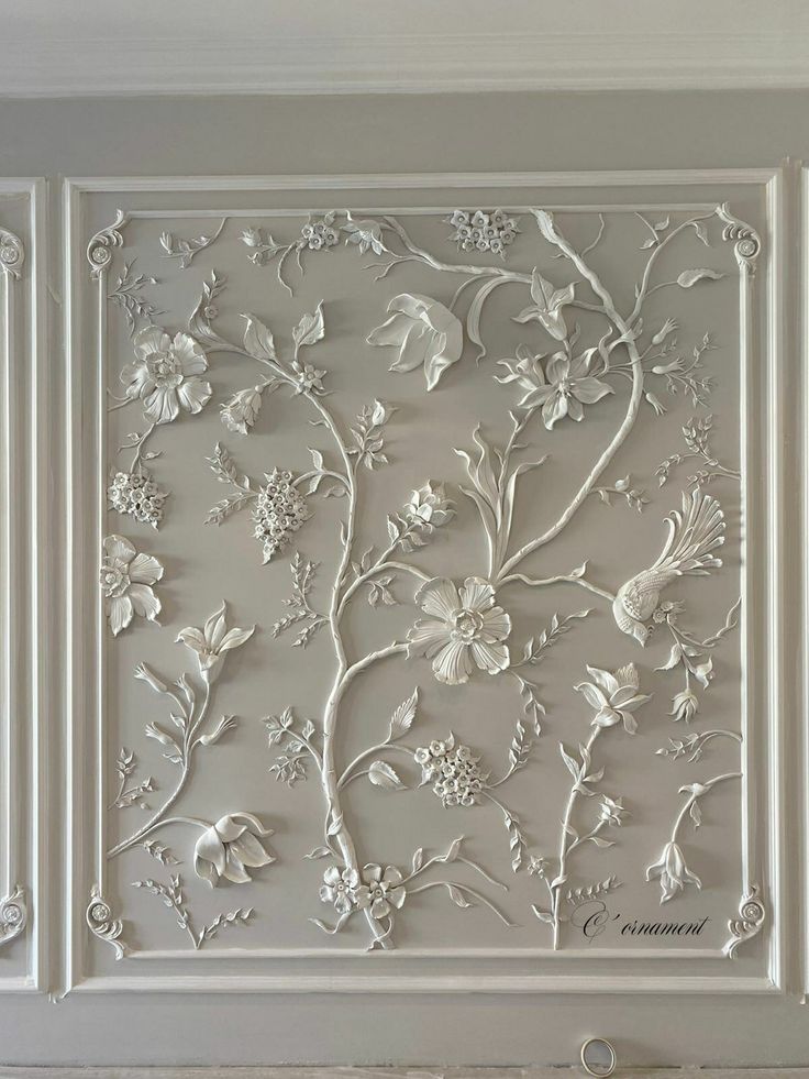 an intricately designed wall panel with flowers and leaves in white, painted on the walls