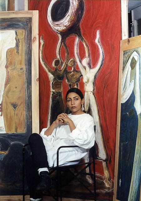 a woman sitting in a chair next to paintings