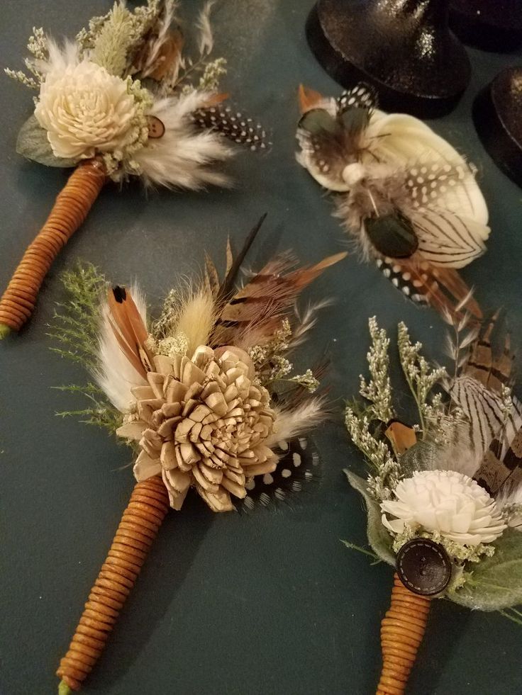 four boutonnieres with flowers and feathers on them sitting on a counter top