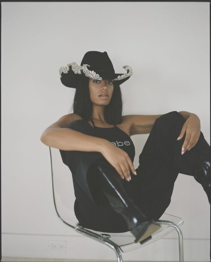 a woman sitting on top of a chair wearing a cowboy hat