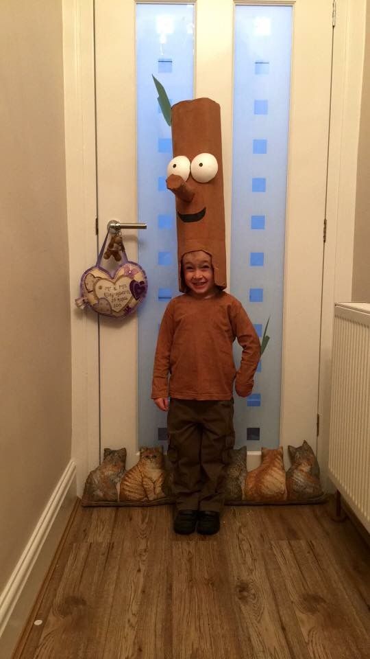 a little boy standing in front of a door with a paper bag on his head