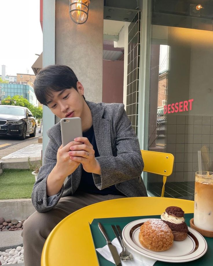 a person sitting at a table with a plate of food and cell phone in front of them