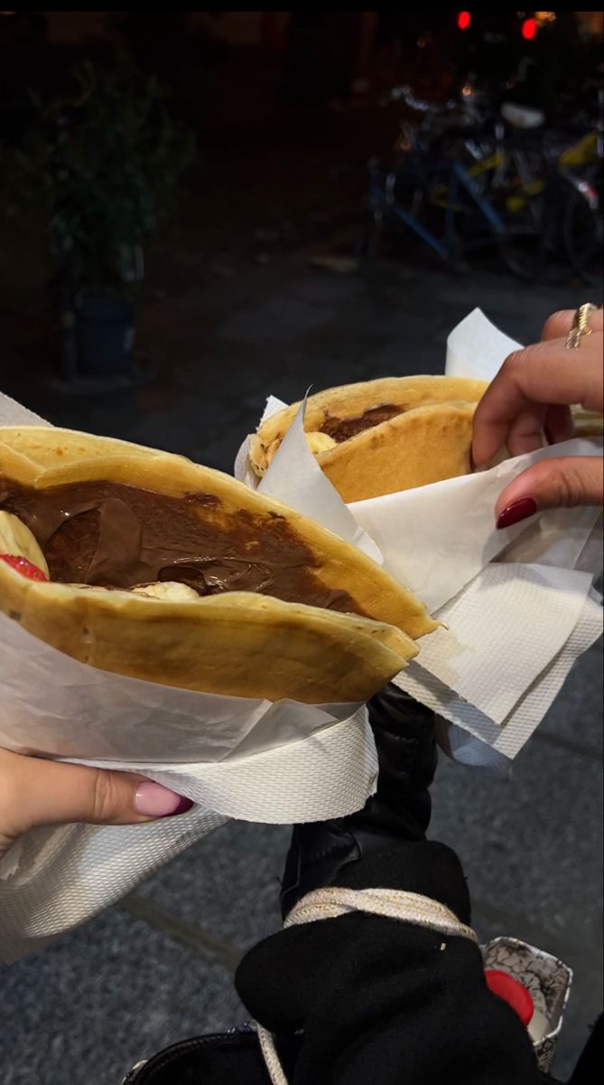 a person holding two large sandwiches in their hands with chocolate filling on the wrapper