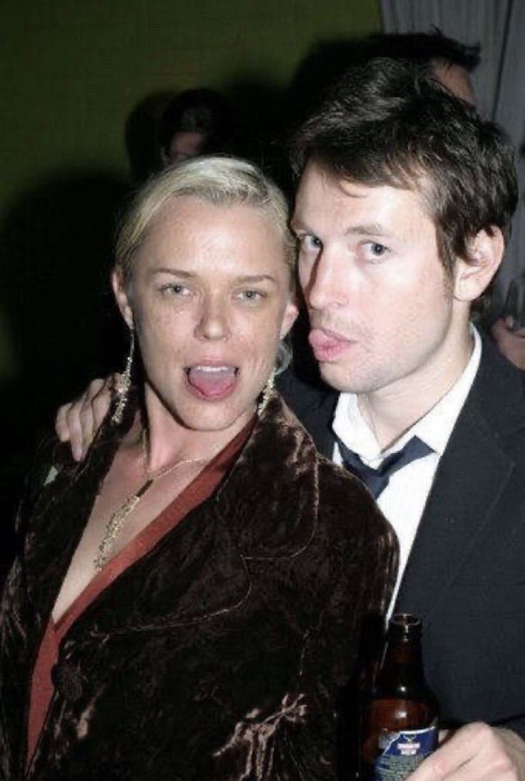 a man and woman posing for a photo with a beer in front of their faces