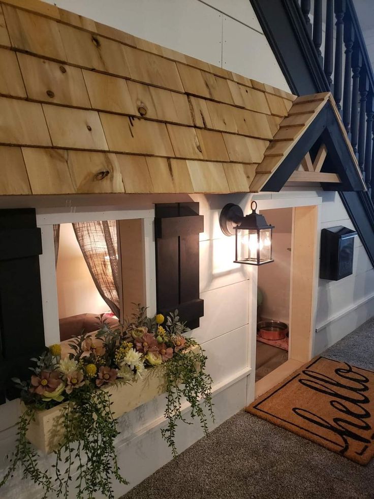 a doll house with flowers and plants in the window sill next to a stair case