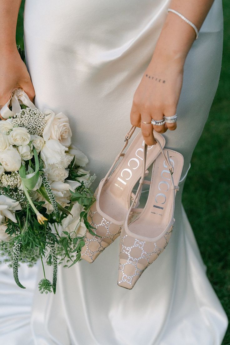 a bride holding her wedding bouquet and high heeled shoes with the word love written on them