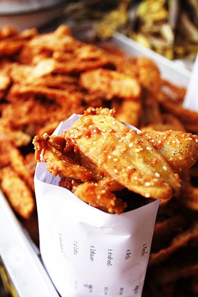 fried food items displayed in trays on display at outdoor market area, closeup