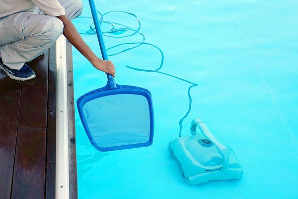 a man kneeling down next to a pool with a net on top of the water