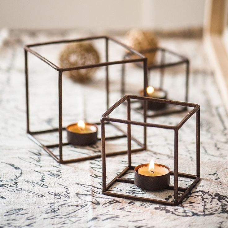 two candles are sitting in metal cubes on the floor