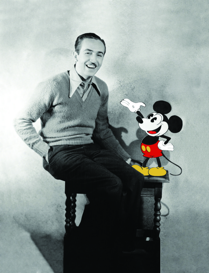 a man sitting on top of a piano next to a mickey mouse