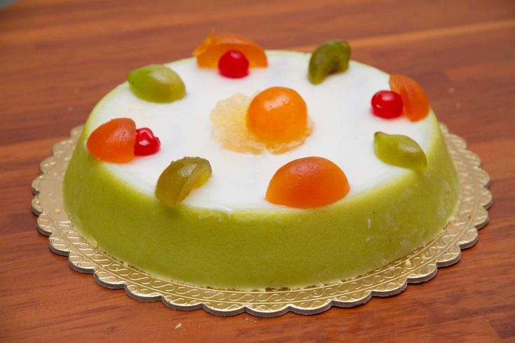 a green cake topped with gummy bears on top of a wooden table