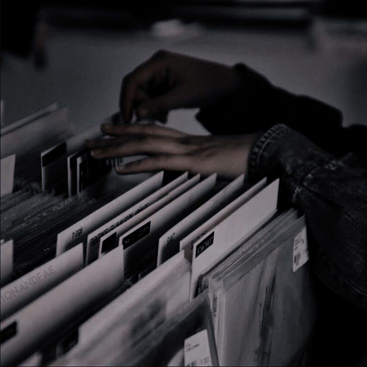 a person's hand on top of a stack of files