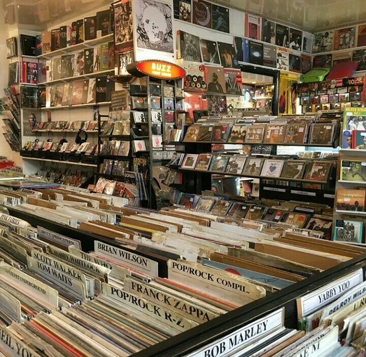 a room filled with lots of books and magazines on shelves next to a wall full of records